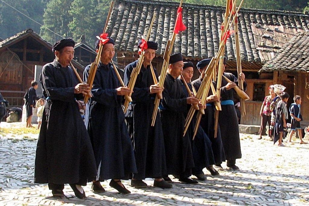 Hombres con vestidos tradicionales tocando la lusheng, zampoña china.