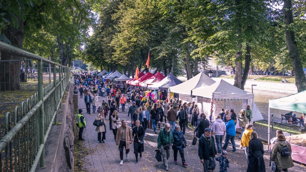 a crowd of people walking around a park with tents